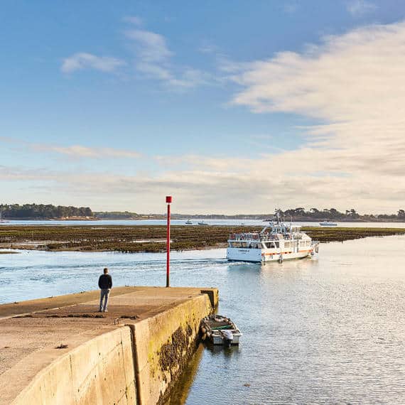 Bateau arrivant au quai sous ciel bleu, homme observant.