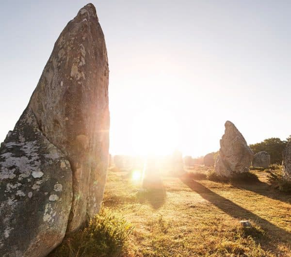 Alignement de menhirs à Carnac illuminé par le soleil.